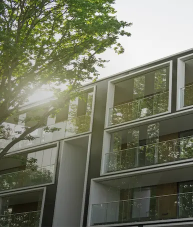 Façade d'immeuble résidentiel moderne avec balcons vitrés et arbres, symbolisant l'efficacité énergétique.