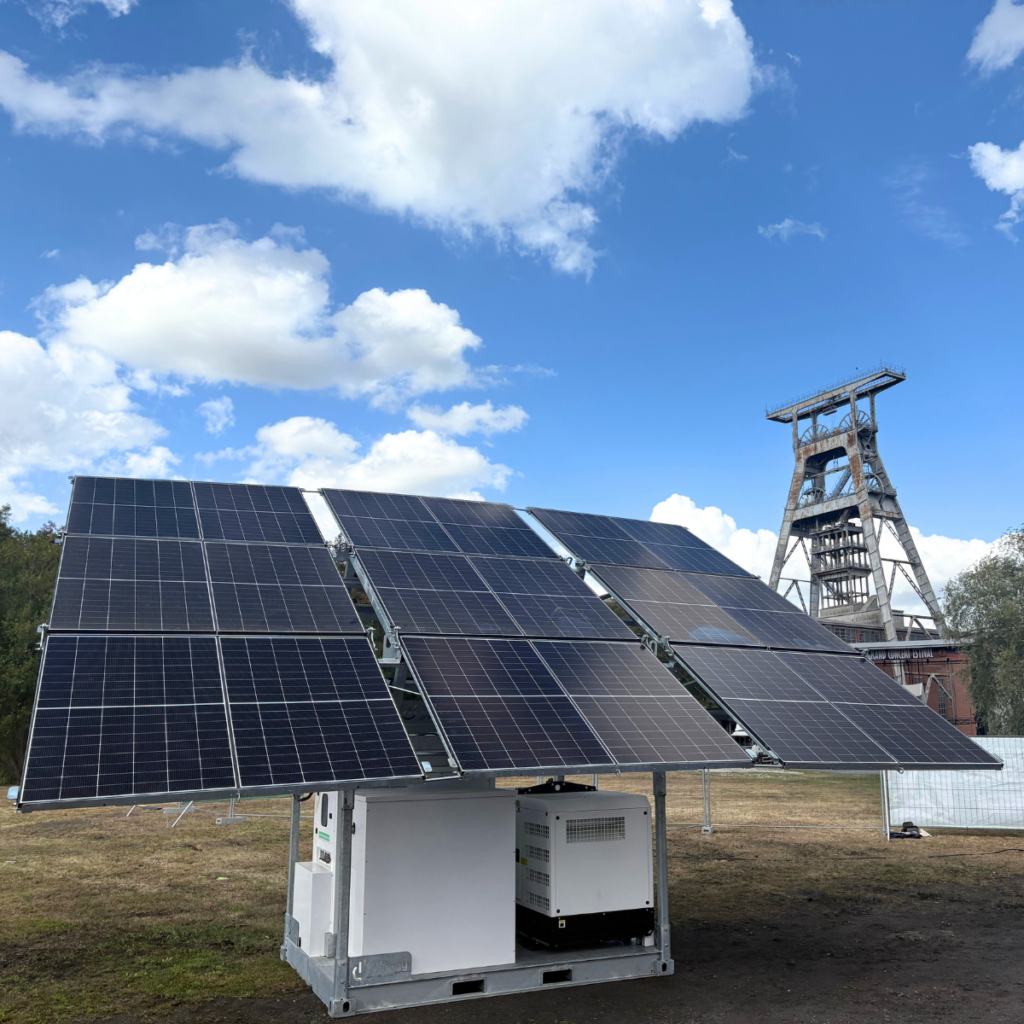 Structure solaire mobile Revolt Energy Green sur skid, installée en extérieur à proximité d'un chevalement minier historique