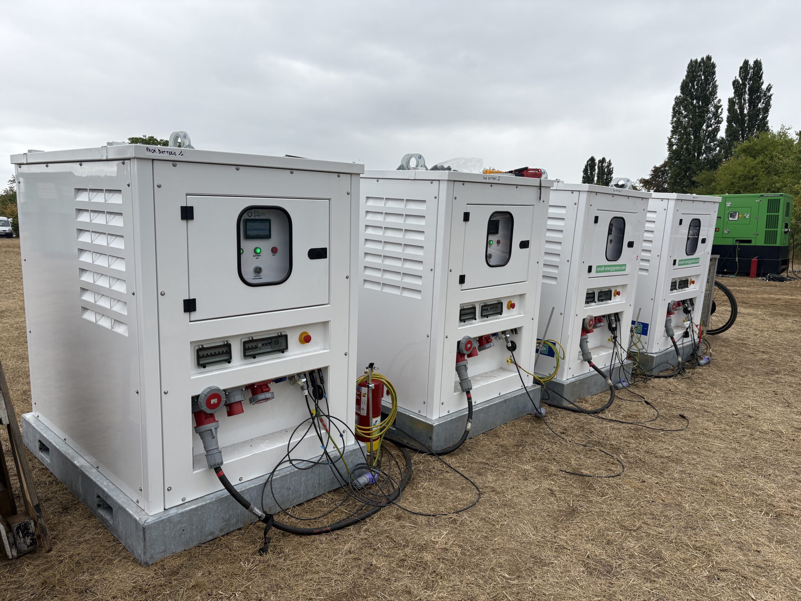 Parc de packs batterie mobiles associés à un groupe électrogène en configuration hybride sur un terrain événementiel